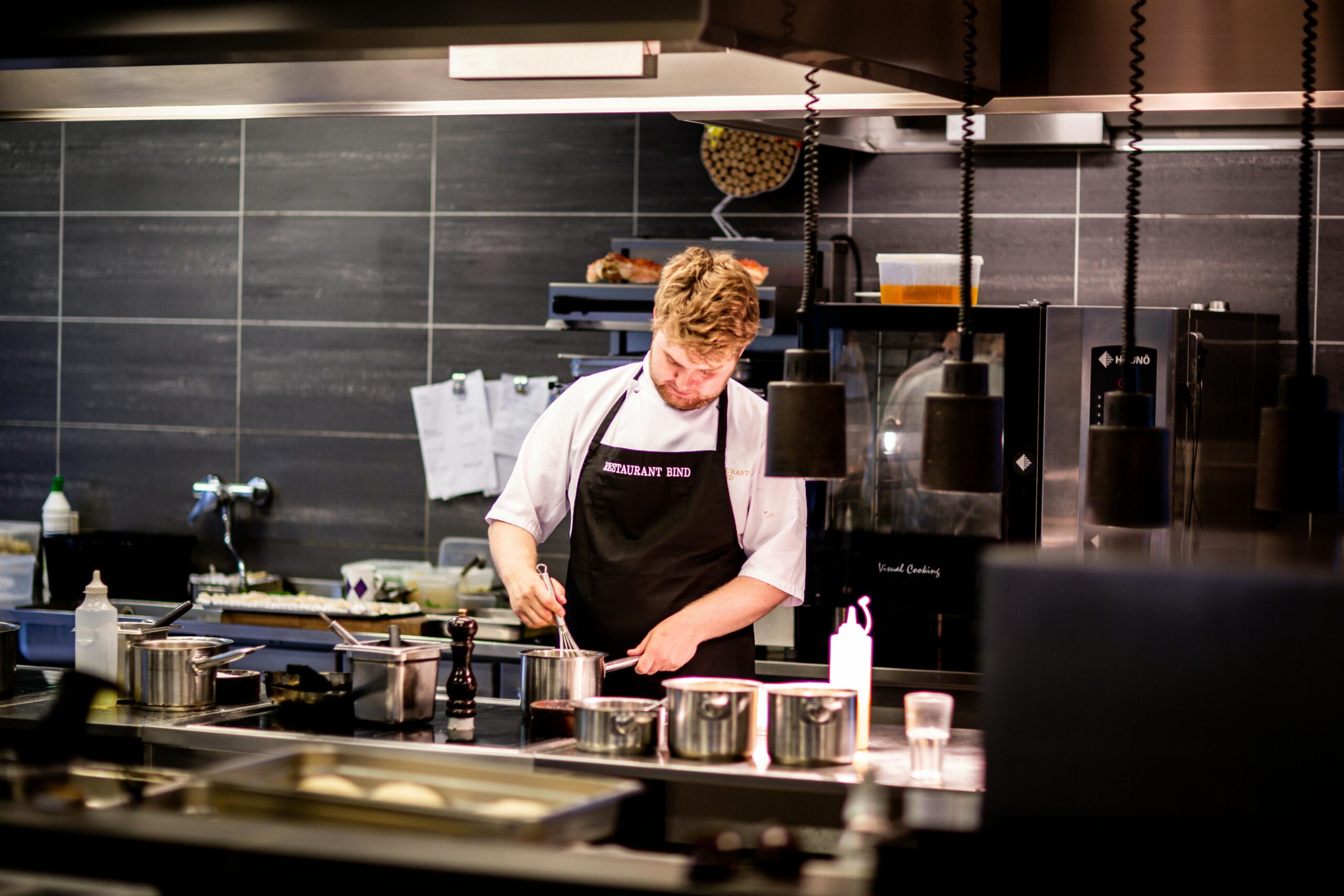 Chef preparing meal in a modern kitchen with various cookware.